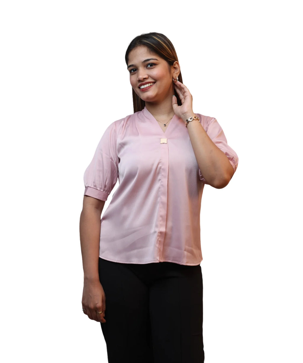 woman wearing a baby pink formal satin blouse with short puff sleeves and black trousers.