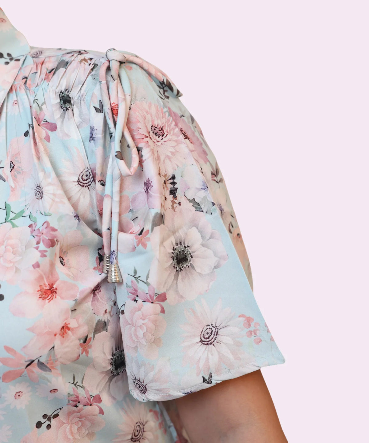 Close-up drawstring shoulder tie with silver tassel tip on women's sky blue floral workwear shirt Ladymade