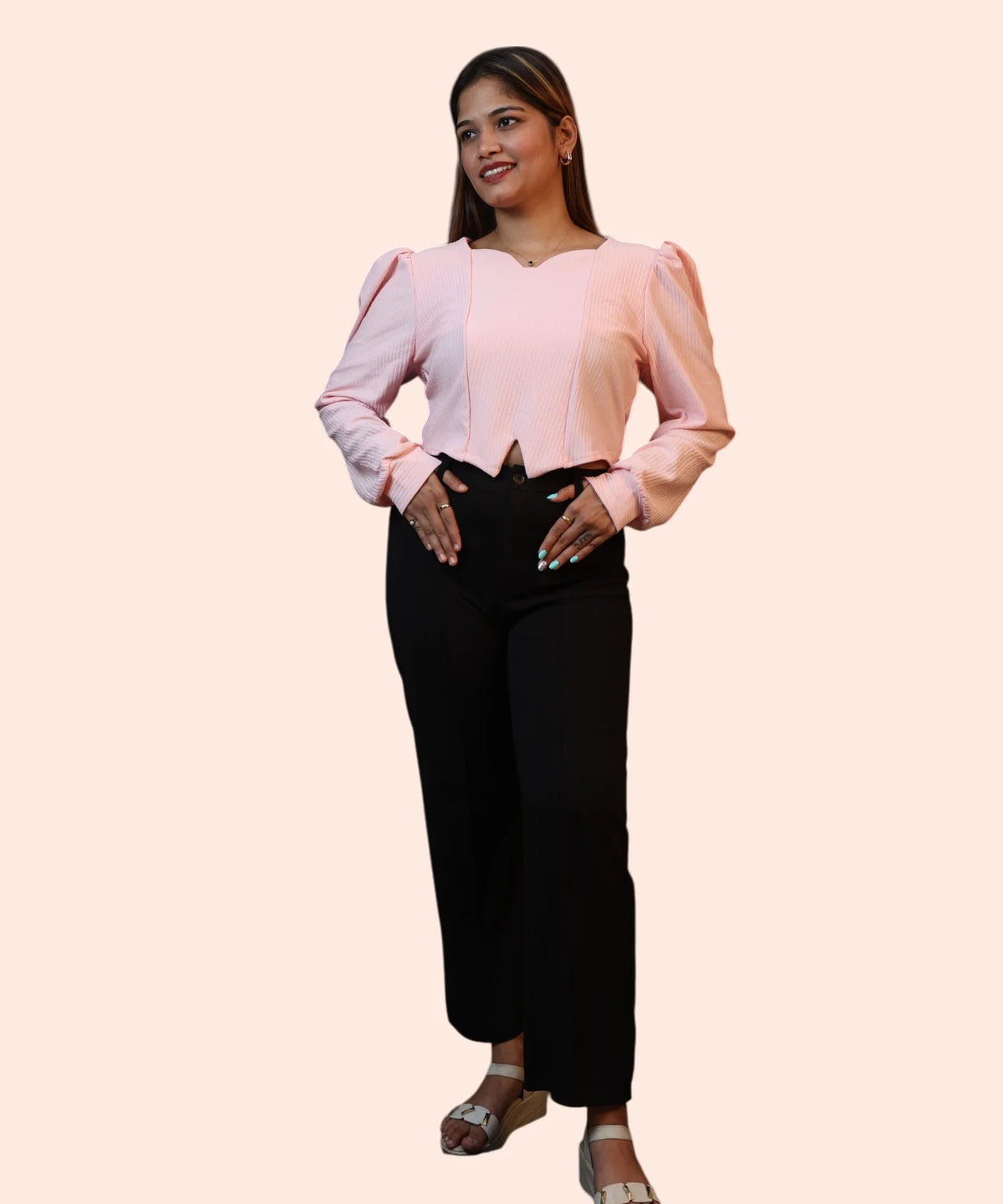 Dynamic candid shot of a woman modeling a baby pink ribbed long sleeve workwear top with an inverted-V hemline by Ladymade.
