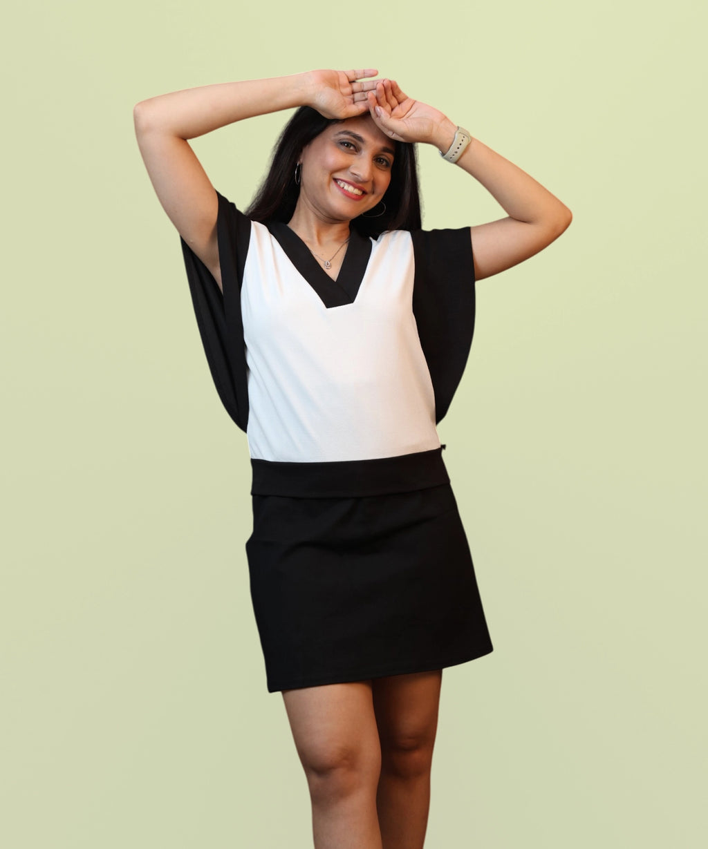 A candid lifestyle portrait emphasizing the relaxed V-neckline and elegant drape on an off-white and jet black corporate top by Ladymade.