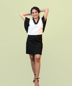 A full-length front view of a woman posing in a monochrome jet black and off-white batwing office blouse by Ladymade.
