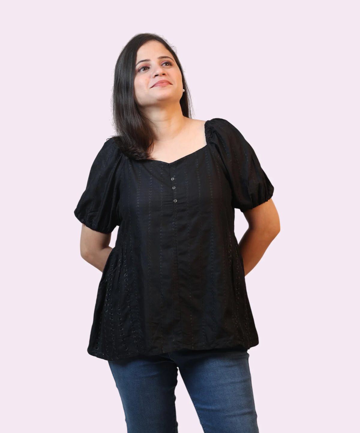 Symmetrical front studio portrait of a woman modeling a premium black schiffli peplum top with puff sleeves by Ladymade.