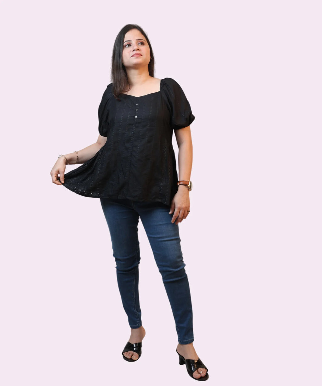Full-length corporate shot showing a woman wearing a black schiffli cotton peplum blouse paired with blue denim jeans by Ladymade.