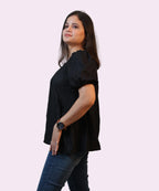 Side profile shot illustrating the gathered puff sleeves and fluid peplum drape of a black corporate top by Ladymade.