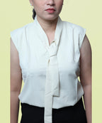 Texture close-up showing the intricate front necktie and mandarin collar on an ivory formal top by Ladymade.