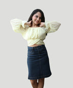 Three-quarter candid photo of a woman wearing an elegant lemon yellow clip-dot chiffon top by Ladymade.