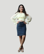 Full-length studio portrait of a woman styling a lemon yellow chiffon crop top with a dark denim skirt by Ladymade.