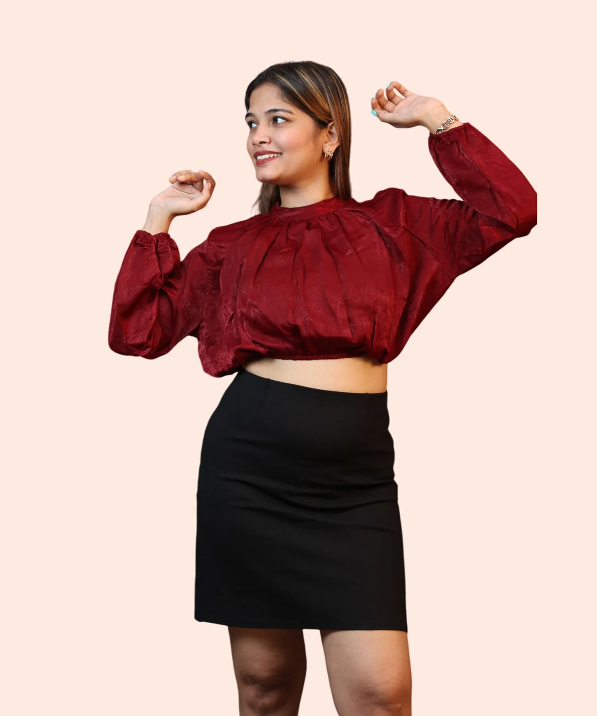 Three-quarter studio pose capturing a woman showcasing the bishop sleeve length of a maroon velvet formal top by Ladymade.