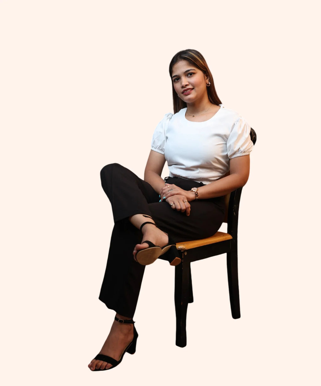 Alternate cross-legged sitting view displaying the waist proportions of an off-white puff sleeve office top by Ladymade.