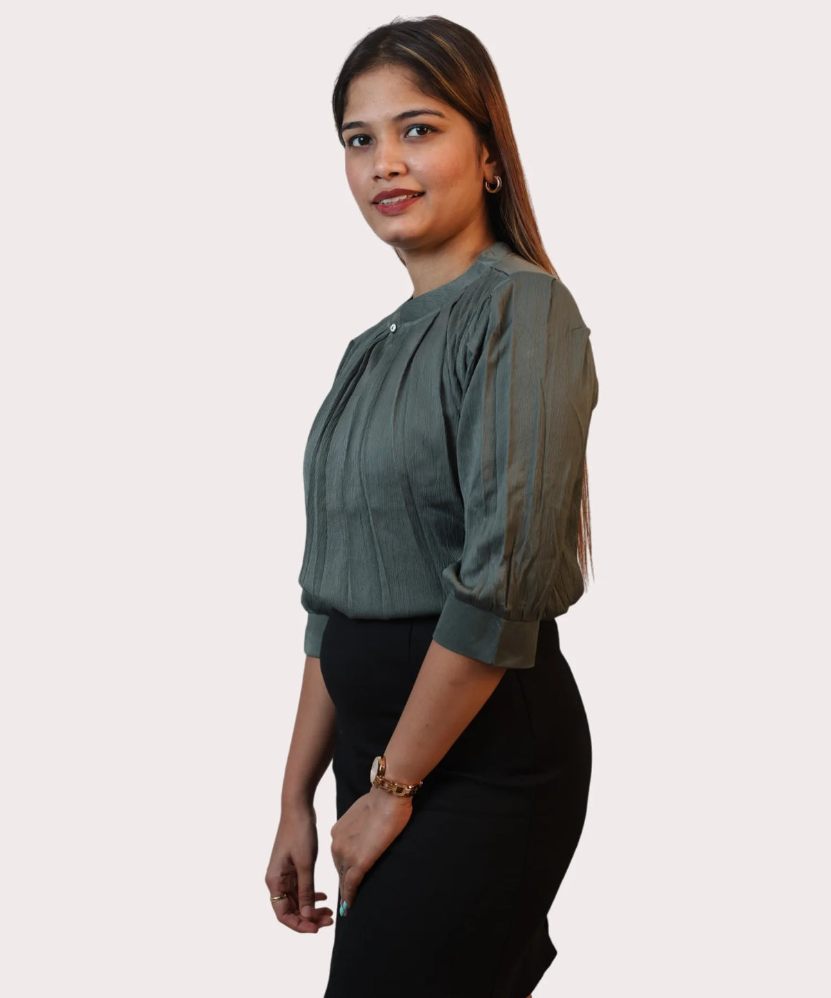 Side profile shot illustrating the three-quarter puff sleeves and fabric drape of an olive green top by Ladymade.