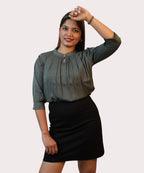 Clear catalogue portrait of a woman posing in a regular-fit olive green pintuck workwear blouse by Ladymade.