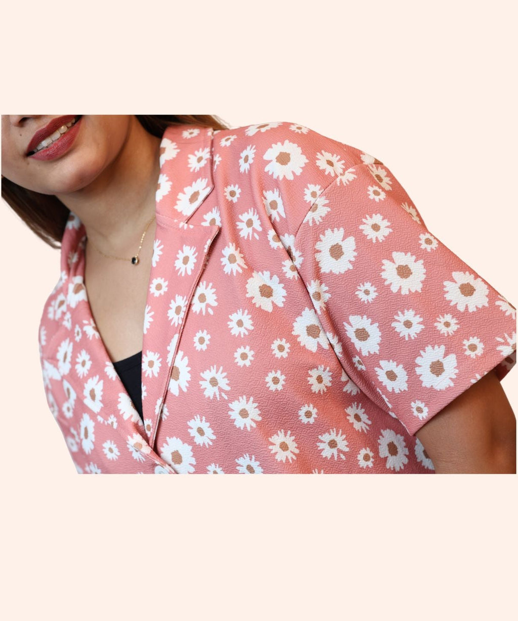 Close-up view highlighting the sharp notch collar and daisy print pattern on a peach pink Lycra blouse by Ladymade.
