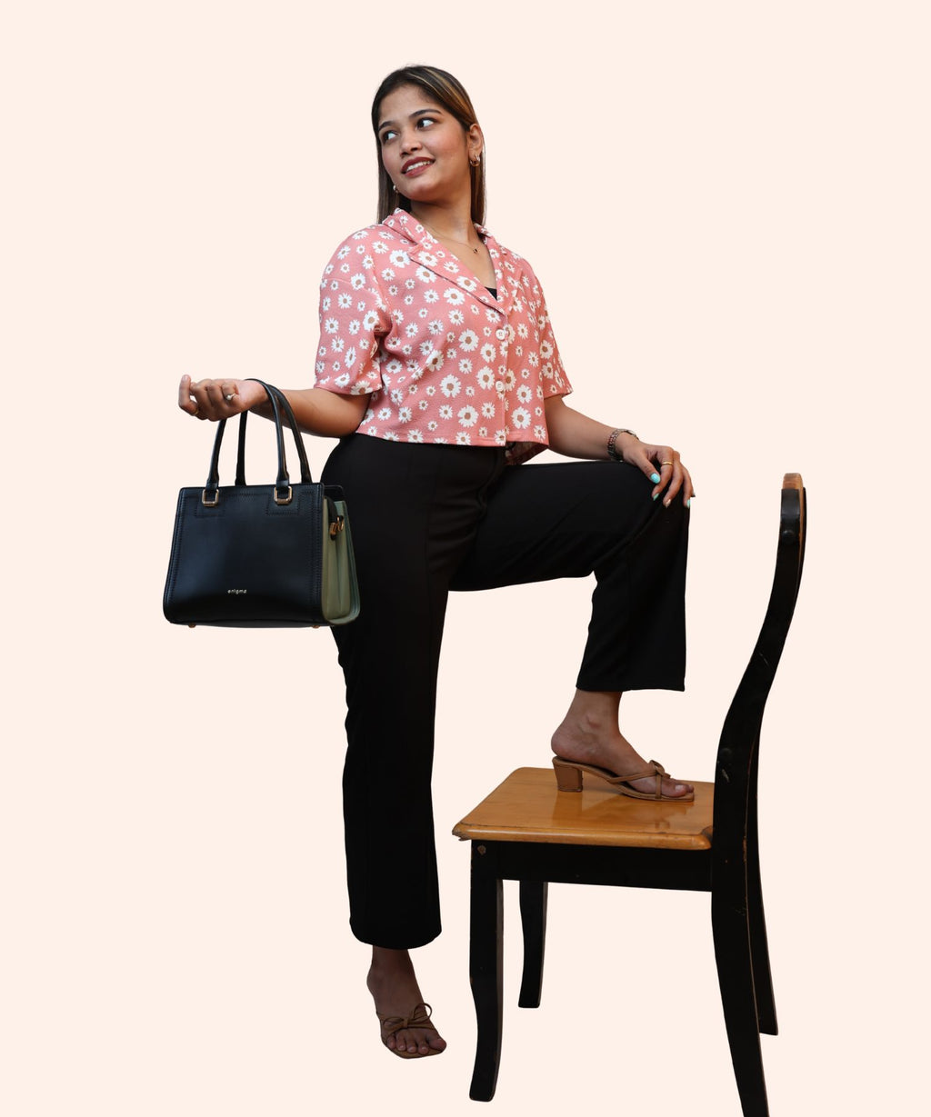 Full standing view of a woman holding a handbag in a peach pink floral workwear crop top by Ladymade.