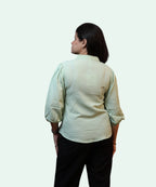 Back view showing the smooth shoulder yoke and fabric texture of a women's pista green cotton office blouse by Ladymade.