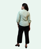 Full back shot showing the regular fit and gathered sleeve cuffs of a pista green cotton formal blouse by Ladymade.