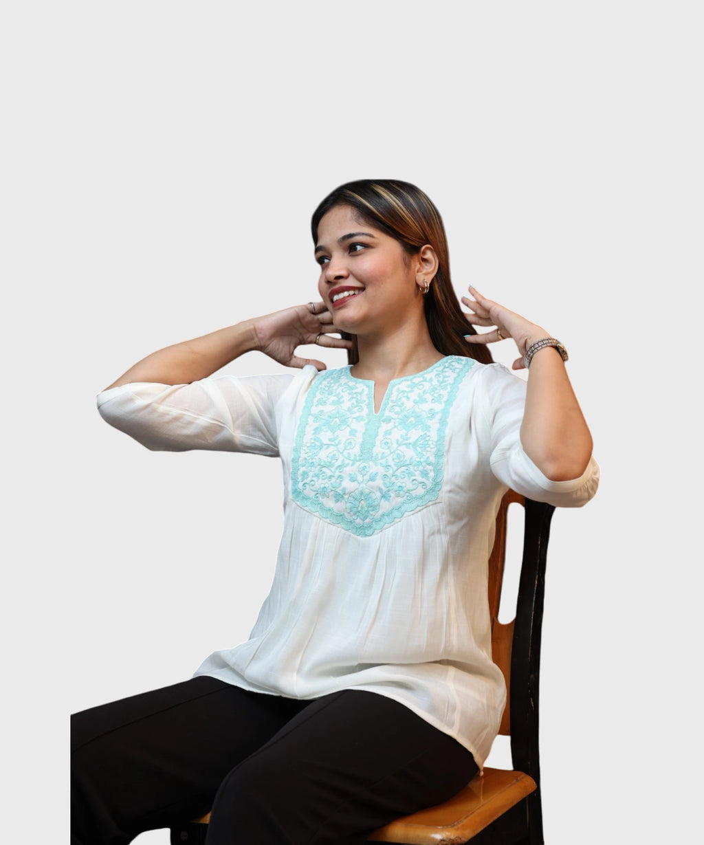 Women's white cotton kurti top turquoise floral embroidered yoke gathered silhouette seated smiling Ladymade