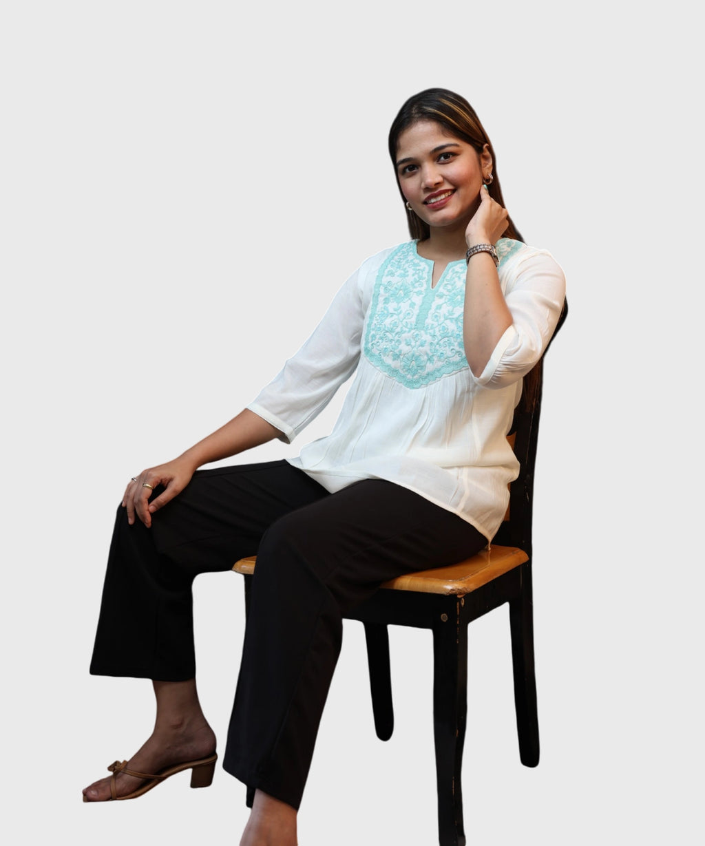 Full length seated women's white cotton kurti top turquoise embroidered yoke black trousers brown heels Ladymade